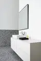 Weißer Waschtisch mit Waschbecken und Chromarmatur. Schwarz-weiße Wandverkleidung aus kleinen Steinchen. Sièhe Ideal Standard Design. Badmöbel mit Schubladen.